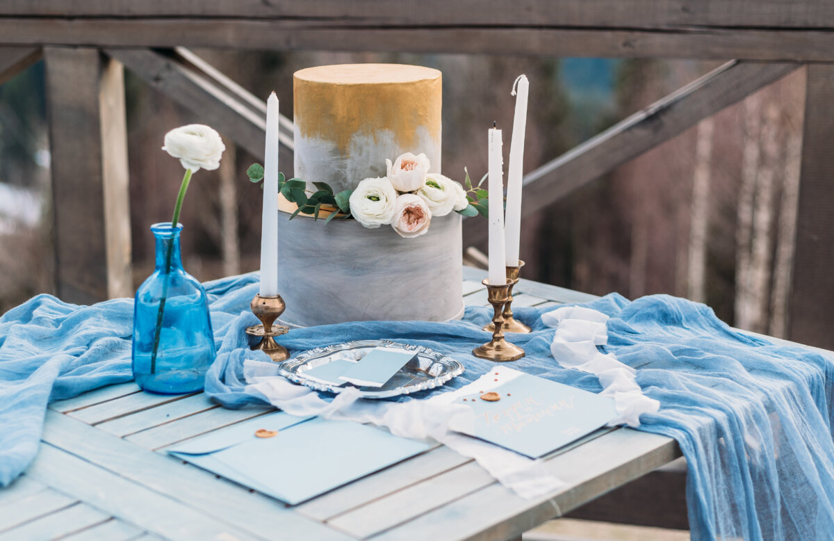 Luxury decorated table and wedding cake for a romantic date. Wedding details: candles, letter, cake on a mountain on background